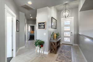 Foyer entrance featuring a chandelier, a healthy amount of sunlight, visible vents, and baseboards