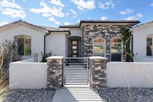 Mediterranean / spanish-style home featuring a fenced front yard, stucco siding, a gate, stone siding, and a tiled roof