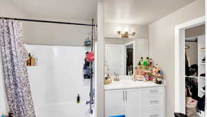 Bathroom featuring shower / tub combo with curtain, vanity, and a textured ceiling