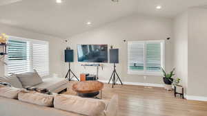 Living room with lofted ceiling and light hardwood / wood-style flooring