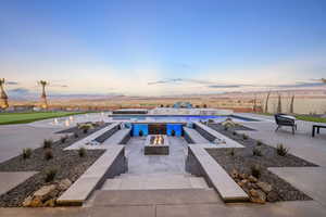 Pool at dusk featuring a fire pit, a patio, and a mountain view