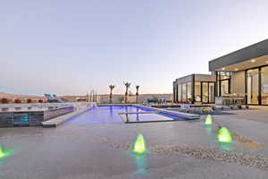 Pool at dusk with a fenced in pool and a patio