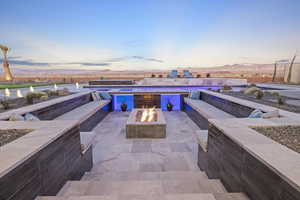 Patio terrace at dusk with a garage, an outdoor fire pit, and a mountain view