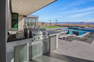 View of patio featuring exterior kitchen, area for grilling, a mountain view, and an outdoor pool