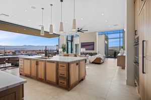 Kitchen with light countertops, hanging light fixtures, open floor plan, a sink, and an island with sink