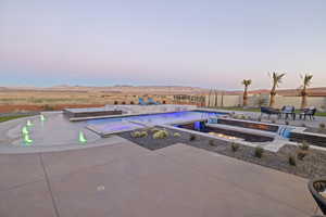 Pool at dusk with a patio area, a mountain view, and a fenced in pool