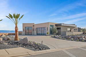 View of front facade with stucco siding, a mountain view, fence, a garage, and driveway