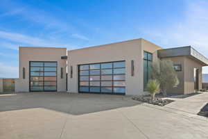 View of front of property with a garage, concrete driveway, and stucco siding