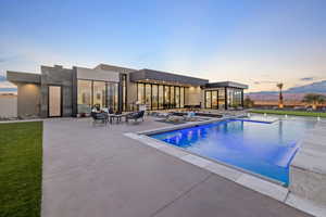 Pool at dusk with an outdoor pool, a patio, and a mountain view