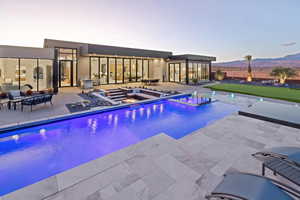 Outdoor pool with a patio area, a jacuzzi, and a mountain view