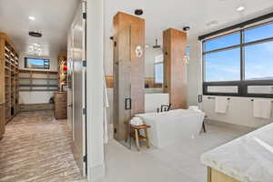 Bathroom with a soaking tub, recessed lighting, a spacious closet, and a stall shower