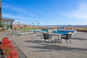 Outdoor pool featuring a patio area, a hot tub, and a mountain view