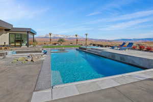 Outdoor pool featuring a mountain view, a patio, and an in ground hot tub