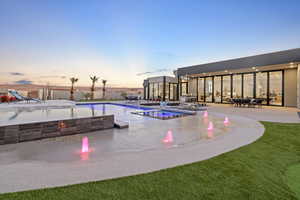 Pool at dusk with a patio area, an outdoor fire pit, and a pool with connected hot tub