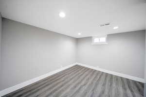 Basement room recessed lighting, baseboards, and wood finished floors