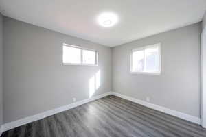 Unfurnished room with baseboards and dark wood-type flooring