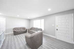 Living area featuring light wood finished floors, baseboards, and recessed lighting