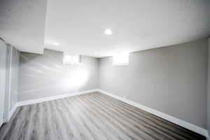 Below grade area featuring a healthy amount of sunlight, baseboards, wood finished floors, and recessed lighting