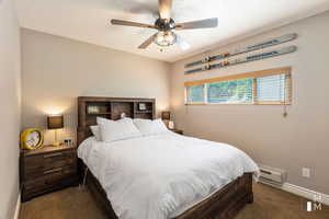 Carpeted bedroom with a baseboard heating unit, ceiling fan, a textured ceiling, and baseboards