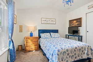 Bedroom with carpet floors and vaulted ceiling