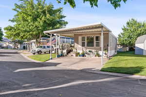 Manufactured / mobile home featuring driveway, a front lawn, and an attached carport