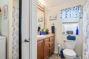 Bathroom featuring baseboards, toilet, washer / clothes dryer, tile patterned flooring, and vanity