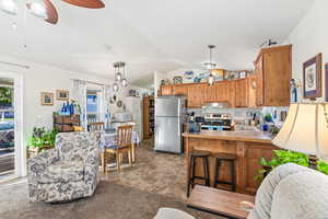 Kitchen featuring lofted ceiling, under cabinet range hood, a sink, light countertops, and appliances with stainless steel finishes