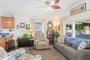 Carpeted living area featuring lofted ceiling and a ceiling fan