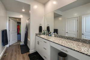 Bathroom with visible vents, baseboards, wood finished floors, curtained shower, and vanity