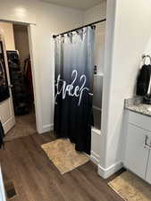 Full bathroom featuring a spacious closet, visible vents, vanity, and wood finished floors