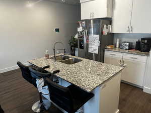 Kitchen featuring a sink, stainless steel fridge, white cabinets, and dark wood-style floors