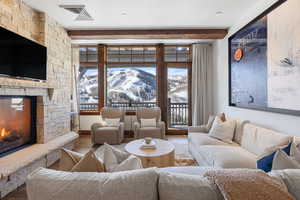 Living area featuring a mountain view, a stone fireplace, wood finished floors, and visible vents