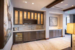 Bar with wine cooler, beam ceiling, visible vents, backsplash, and a sink