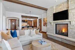 Living room with baseboards, visible vents, wood finished floors, a fireplace, and beam ceiling