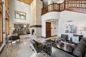 Living area with marble finish floor, recessed lighting, a high ceiling, a stone fireplace, and baseboards