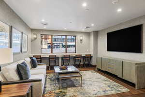 Living room with wallpapered walls, wood finished floors, visible vents, and recessed lighting