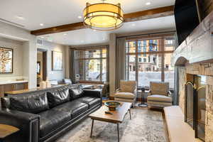 Living room featuring visible vents, wood finished floors, beamed ceiling, a stone fireplace, and recessed lighting