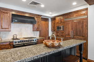 Kitchen with tasteful backsplash, visible vents, high end appliances, ventilation hood, and recessed lighting