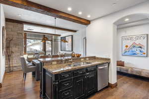 Kitchen featuring a sink, dark cabinets, dark wood-type flooring, and stainless steel dishwasher