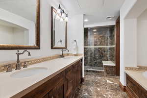 Bathroom featuring double vanity, tiled shower, a sink, and visible vents