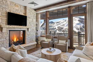 Living area with visible vents, a stone fireplace, and wood finished floors