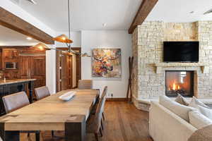 Dining room featuring dark wood-type flooring, a fireplace, beam ceiling, and baseboards