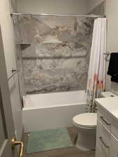 Full bathroom with shower / bath combination with curtain, vanity, toilet, and wood finished floors
