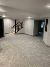 Basement with carpet floors, visible vents, stairway, and baseboards
