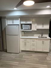 Kitchen featuring light wood finished floors, white appliances, a sink, and recessed lighting
