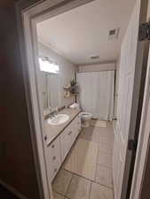 Bathroom featuring curtained shower, visible vents, toilet, vanity, and tile patterned floors