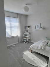 Carpeted bedroom with baseboards, visible vents, and a textured ceiling