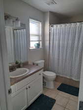 Full bath with curtained shower, toilet, vanity, visible vents, and tile patterned floors