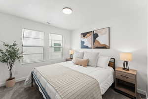 Bedroom featuring a textured ceiling, carpet floors, visible vents, and baseboards