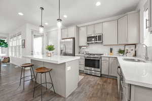 Kitchen featuring decorative backsplash, a kitchen island, stainless steel appliances, a kitchen bar, and a sink